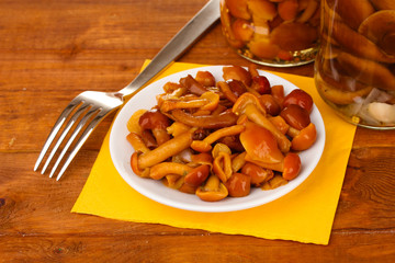 Marinated mushrooms in saucer on wooden table