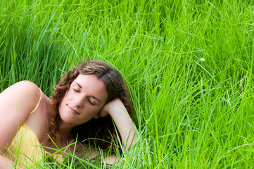 Country girl relaxing in a meadow of long green grass
