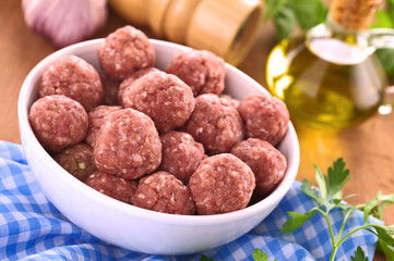 Raw meatballs with garlic in a white bowl (Selective Focus)