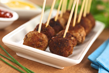 Meatball appetizers with toothpicks and sauces on the side