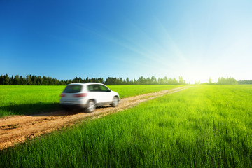 Obraz na płótnie Canvas pole wiosną i blured samochód na drodze gruntowej
