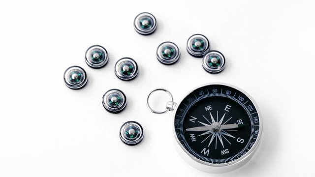 Nine small black plastic compasses and one big isolated