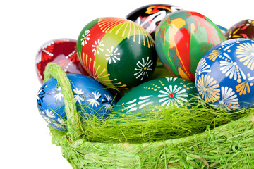 Colorful painted easter eggs in green basket isolated on white
