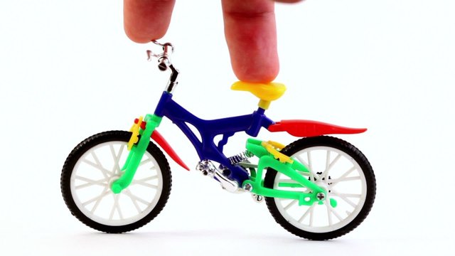 Fingers on toy bike, rotates handlebars, then ride away