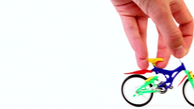 Hand does jump trick on toy bike