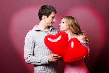 Fototapeta na wymiar Portrait of two young people holding heart-shaped balloon