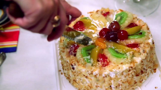 Hands severs sweet fruit cake by knife