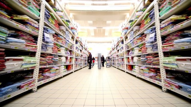 Few people walk among shelves with goods in hypermarket