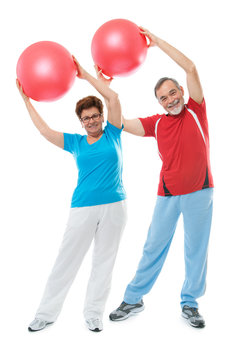 Senior Couple Doing Fitness Exercise With A Ball In Gym