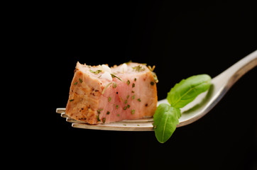 Slice of pork fillet on a fork seasoned with herbs