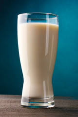 glass of milk on wooden table on blue background