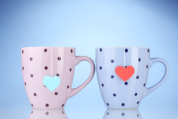 Two cups and tea bags with red and blue heart-shaped label
