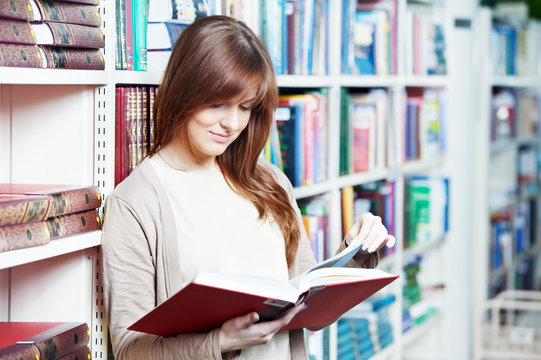young student girl reading book in library