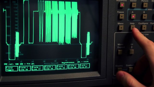 Hand push buttons and rotates knob on oscilloscope
