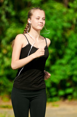 Fototapeta premium Young woman running in green park