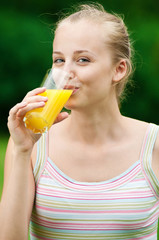 Young woman drinking orange juice. Outdoor