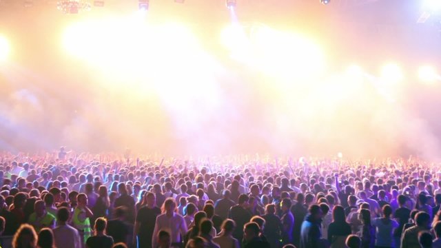 Many people at rave party, view from behind