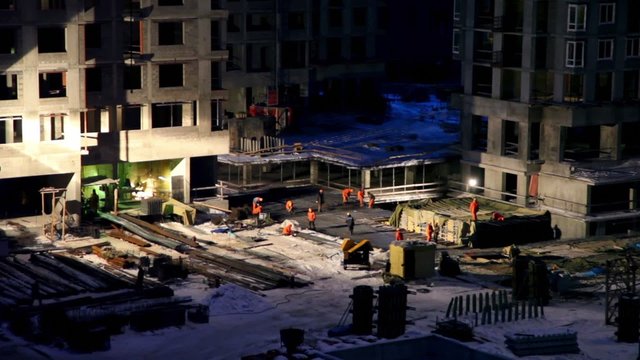 Labourers work at construction site on winter night