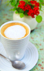Cup of cappuccino with flower on the table