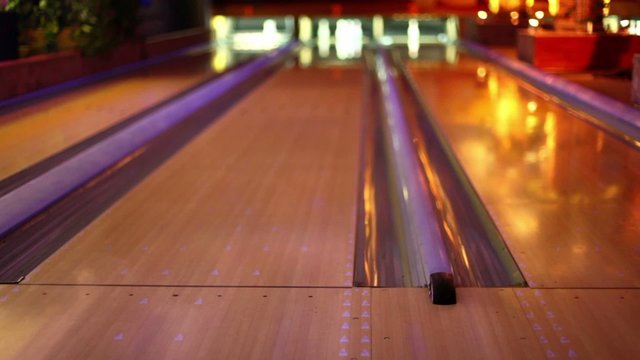 Girl throw bowling ball on middle lane of three in club