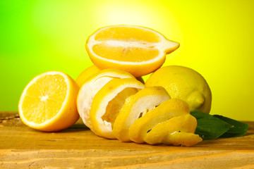 ripe lemons with leaves on wooden table on green background