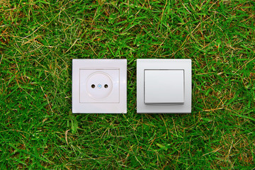 green energy concept: electric outlet and light switch on grass