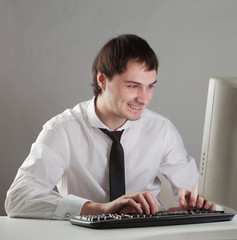 young man at the computer happy, looking at the monitor