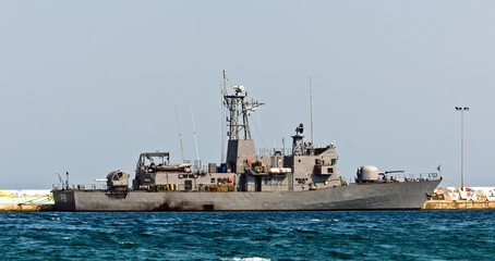 Big battle ship in the dock against blue sky and mountains