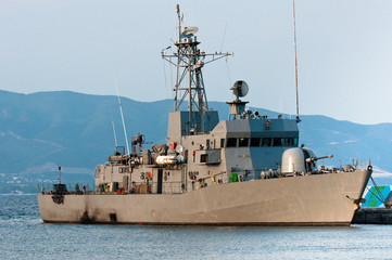 Big battle ship in the dock against blue sky and mountains