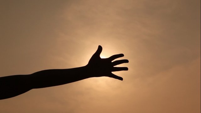 hand with an open palm moves against sun as if concerning it