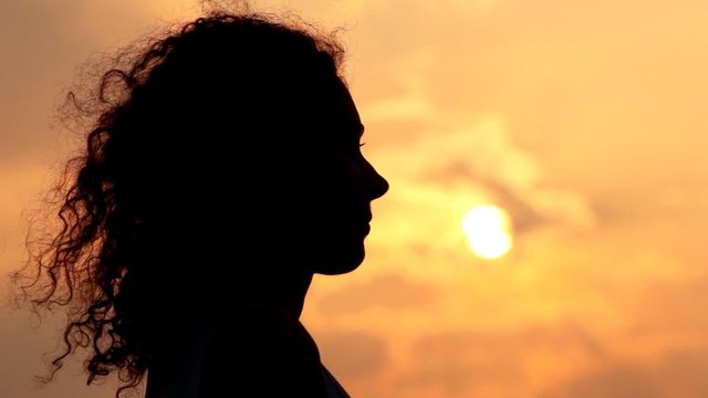 head smiling woman against sunset and cloud on sky