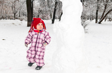 child looking at snowman