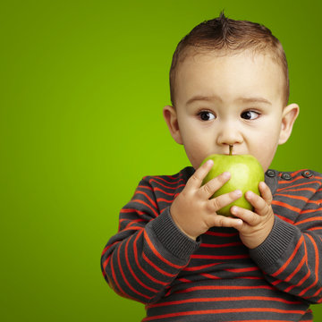 portrait of a handsome kid bitting a green apple over green back