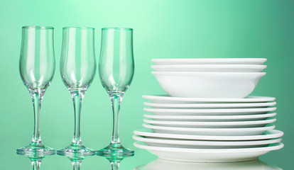 Clean plates and glasses on green background