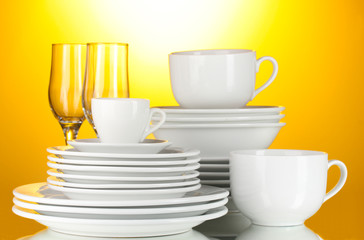 empty bowls, plates, cups and glasses on yellow background