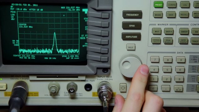 Hand push buttons and rotates knob on oscilloscope