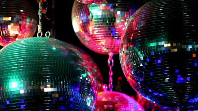 Several discoballs hang on chain and rotate