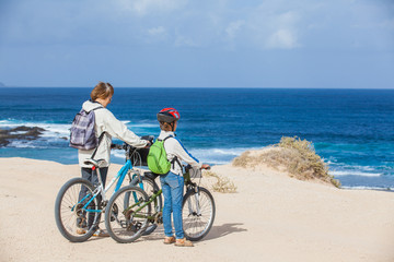 Obraz premium girl and her grandmother on bikes on the beach