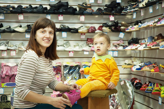 woman with child chooses baby shoes