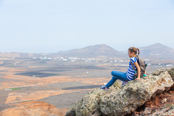 Naklejka na ściany i meble girl sitting on cliff's edge, looking to a sky
