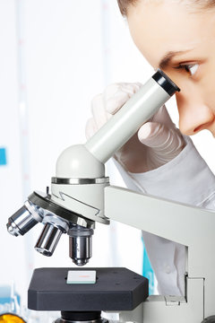 Scientist looking through a microscope in a laboratory closeup