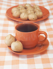 Profitroles and cup of tea on tablecloth