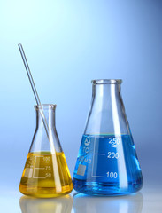 Two flasks with yellow and blue liquid with reflection