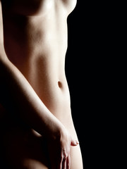 Körper einer  nackten Frau vor schwarzem Hintergrund