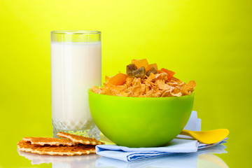 tasty cornflakes in green bowl and glass of milk