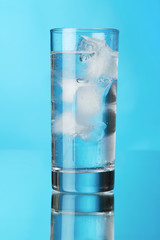 Glass of ice water on blue background