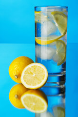 Glass of lemon ice water on blue background