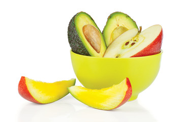 Sliced fresh apple, avocado in ceramic cup and mango
