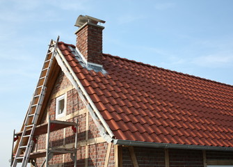 Neu eingedecktes Fachwerkhaus, mit Gerüst und Leiter, in Hamm-Bockum Hövel bei blauem Himmel.