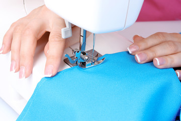 sewing machine, blue fabric and women's hands